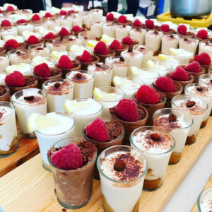 Rows of vegan dessert shot glasses topped with raspberries served at a UK wedding by Vegan Junkies