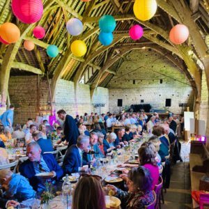 Guests enjoying a vegan wedding breakfast in a stunning barn venue decorated with colourful lanterns