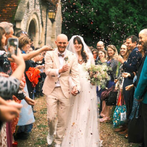 Vegan Bride and groom walking through confetti surrounded by cheering guests outside a UK church
